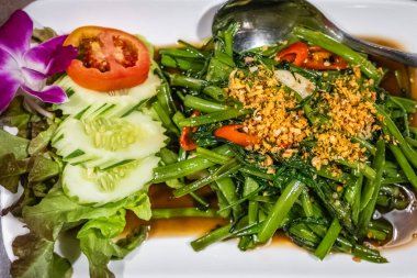 Asya restoranında geleneksel vejetaryen yemeği. Çin Sabah Zaferi ya da restoranda pişirilmiş istiridye soslu su ıspanağı. Asya yemeği tarzı. Beyaz tabakta karıştırılmış su ıspanağı.