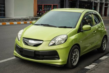 Caddeye park edilmiş 4 kapılı yeşil bir arabanın ön görüntüsü. Şehir dışında park edilmiş modern kompakt araba. Hatchback arabasının yakın görüntüsü. Hiç kimse, seçici odaklanma