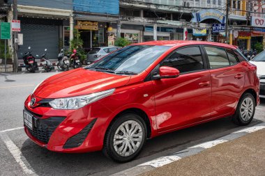 Toyota Hatchback arabası yol kenarındaki beyaz çizginin yanındaki bir şehir sokağında park edilmiş. Kırmızı Toyota Vios, Phuket Thailand şehir merkezindeki kaldırıma park etmiş. Şehir merkezinde modern kompakt tasarım otomobil 24 Temmuz 2024