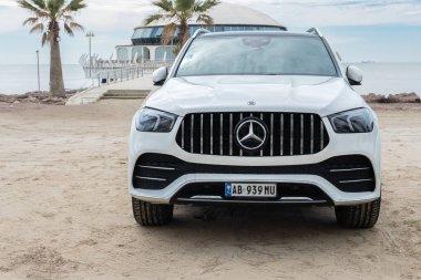 Caddeye park edilmiş 4x4 off-road 'lu lüks Mercedes GLE' nin ön görüntüsü. Beyaz Mercedes-Benz GLE Coupe plajda park halinde. Hiç kimse, editör-Durres Arnavutluk-Nisan 1.2025