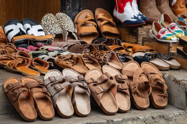 Sokak pazarı kaliteli deri ayakkabılar ve sandaletler satıyor. Yaz ayakkabıları, değişik parmak arası terlikler, raflarda asılı renkli sandaletler. Asya Vietnam 'da bir cadde boyunca bir markette ayakkabı satışı.