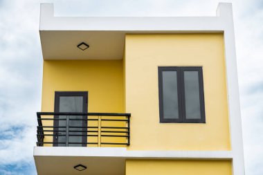Balkonu olan modern bir apartman dairesi. Yeni yerleşim yerleri kompleksi. Güzel pencereleri ve balkonu olan sarı bir evin tepesinde. Güzel bir ev dış görünüşü. Gayrimenkul Dış Mekanı.