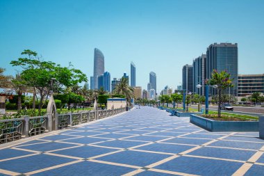 Şehir parkında yeşil ağaçlarla güzel bir yürüyüş. Abu Dabi, BAE 'deki Corniche gezinti alanı. Sahil şeridi boyunca Corniche Bulvarı plaj parkı. Seyahat fotoğrafı, yaz tatili konsepti.