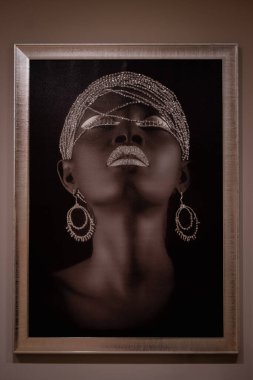 Güzel siyah kadın portrenin çerçevesinde bir model. Duvarda asılı duran genç ve güzel bir Afrikalı kadının portresi. Editör, seçici odak, Tiran Arnavutluk-8. 2025