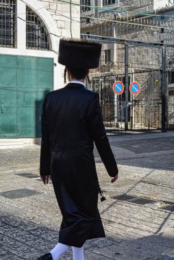 Kudüs 'ün eski bir şehrinde geleneksel giysileri olan aşırı ortodoks Yahudi. Kudüs İsrail 'in bir caddesinde yürüyen, kürk şapkalı Hasidik bir adamın dikiz görüntüsü. Seyahat fotoğrafı, seçici odak