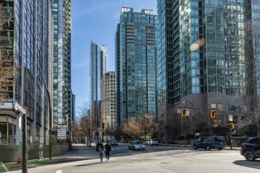 Yüksek binaları olan işlek şehir sokakları. Şehir manzarası, arka planda yüksek binalar olan Vancouver caddesinde arabalar ve yayalar var. Seyahat fotoğrafı, editör - Mar 6.2022