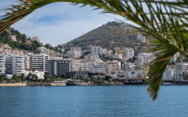 Arnavutluk tatil beldesi şehri. İyon deniz manzaralı Saranda kıyı kenti manzarası. Turistik bir şehrin gezinti alanı. Arnavutluk Limanı, Avrupa. Seyahat konsepti arka planı.