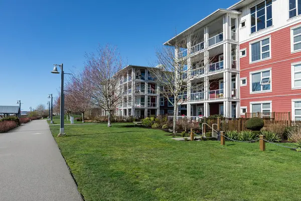 Yeşil çimenliği ve geçidi olan modern yerleşim yerleri. Konut geliştirme. Vancouver Canada 'da mavi gökyüzü olan yeni apartmanlar. Uzayı kopyala, seyahat fotoğrafını çek, kimseyi