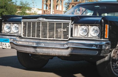 Amerikan Chevrolet Old-Time Kahire yolunda ilerliyor. 1974 model Chevrolet Impala 4 kapılı kaslı arabanın ön farları. Retro siyah araba. Sokak fotoğrafı, hiç kimse, editör - 17 Aralık 2023