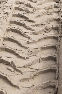 Kumda lastik izleri. Kumdaki tekerlek izlerini kapat. Büyük lastik izleri. Plajda traktör lastik izleri var. Yerde büyük kamyon tekerleği izleri var. Kimse.