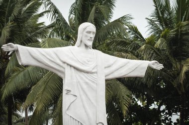 Aziz Antony Siolim Goa Hindistan Kilisesi 'nin Kurtarıcı İsa heykeli. Arka planda palmiye ağaçları olan açık kollu bir heykel. Seyahat fotoğrafı, kimse yok.