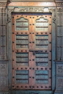 Geleneksel çift katlı ahşap kapılar. Hindistan 'daki eski kırsal evlerde, eski, çatlak dokuları, demir sapı ve eşsiz oyulmuş süslemeleri olan. Kırsal, süslü çerçeveli eski ahşap kapı..