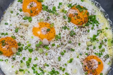 Yağda yumurta ve taze soğanlı kahvaltı. Güneş gören yumurtalar, paslanmaz çelik bir tavada kızarmış yumurtalar. Sağlıklı keto yemeği. Üst görünüm