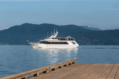 Modern yolcu tur teknesi denizde. Göl manzarası ve arkasında dağlar olan büyük beyaz bir yat. Boş ahşap güverte. Sürat teknesi gölde yüzüyor. Seyahat tatilleri ve tatil konsepti