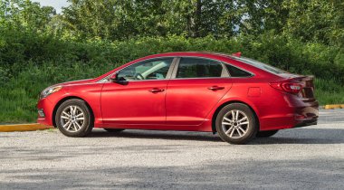 Caddeye park edilmiş modern kırmızı arabanın yan görüntüsü. Otoparka park edilmiş kırmızı spor araba. Kimse.