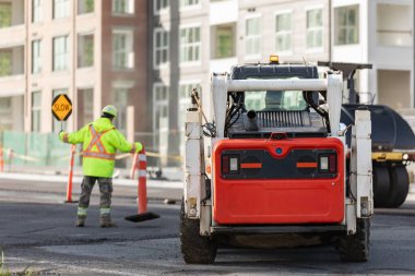 İşçiler ve asfalt makineleri. Asfalt yenileme, yol onarımı, güvenlik için plastik bariyerler kurulmuş. Yeni asfalt kaplaması için eski yüzeyi öğütüyorum. Eski asfalt yüzeyinin öğütülmesi, kaldırılması