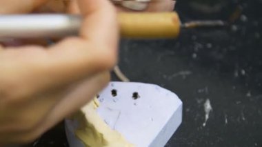 Diş teknisyeni diş kaplaması ve protez kalıpları üzerinde çalışıyor. Diş kliniğinde seramik protez üretimi. İmplantlar için seramik diş başlıkları. 