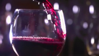 Kırmızı şarap güzel bir bardağa doldurulmuş. Bir barmen bardağa kırmızı şarap döker. Şarap üretimi ve satışı. 