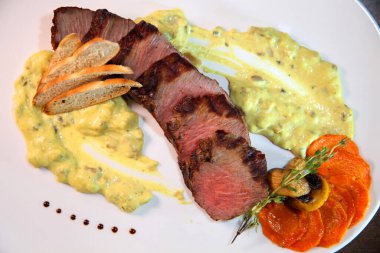 Biftek orta kızartma, kremalı mantar sos parçalar halinde kesin. Bir beyaz plaka ve ahşap masa biftek servis.