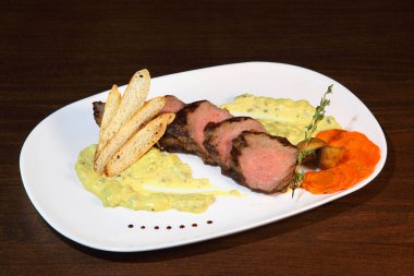 Biftek orta kızartma, kremalı mantar sos parçalar halinde kesin. Bir beyaz plaka ve ahşap masa biftek servis.