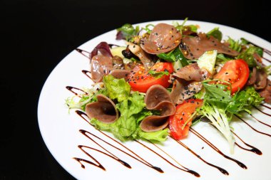 Salata sebze ve otlar, sığır eti dilim giyinmiş beyaz tabakta sos ile.