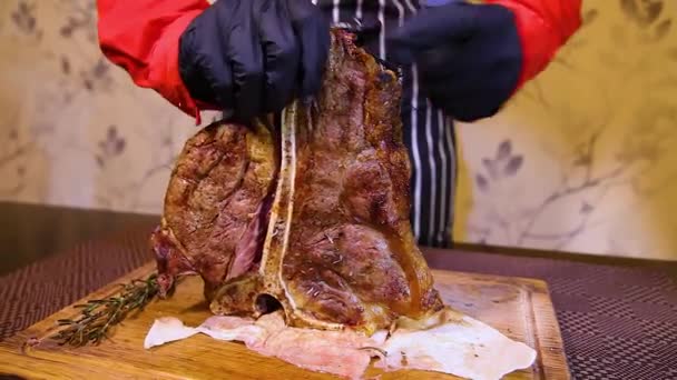 一个戴着手套的侍者把一块多汁的牛排切成薄片 餐馆的厨师把一份中等程度的牛排切成薄片 肉眼牛排 — 图库视频影像