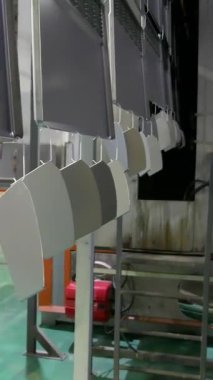 Taşıyıcı hat boyası. Fabrikadaki boyacı. Damgalı parçalar boyanıyor. Metal ürünlerin damgalı parçaları fabrikada boyanır. Dikey video.