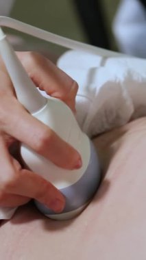 Hamile bir kadının cenininin ultrason muayenesi. Ultrasonik tarayıcı. Ultrason muayenesi için cihaz. Dikey video.