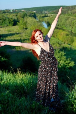 Kırmızı bluzlu ve beyaz kotlu bir kız kameraya doğada poz veriyor. Neşe, mutluluk, huzur. Bir kız doğada bir fotoğrafçıya poz verir..