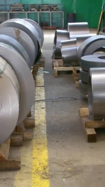 Fabrikadaki ürünlerin basın tarafından oluşturulması için çelik rulolar. Bobinli çelik çarşaf. Dikey video.