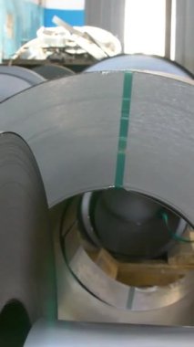 Fabrikadaki ürünlerin basın tarafından oluşturulması için çelik rulolar. Bobinli çelik çarşaf. Dikey video.