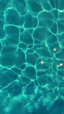 İnanılmaz ve güzel kristal berrak mavi su. Güneşin parlaklığı suya yansıtılır. Kamera merceğinin yarattığı güzel güneş yansıma efekti. Dikey video.