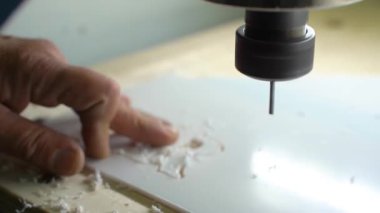 Fabrika işletmecisi plastikten harfler kesiyor. Değirmen makinesi. Bir değirmen makinesi plastik bir çarşaftan harfleri keser..