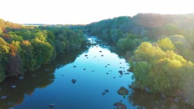 Akıntılı nehir. Nehir kenarındaki güzel sonbahar doğası. Gün batımında nehirler ve akıntılar. Gökyüzünün yansıması ve sudaki ağaçlar. Hava görünümü.