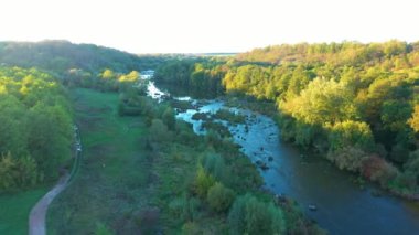 Akıntılı nehir. Nehir kenarındaki güzel sonbahar doğası. Gün batımında nehirler ve akıntılar. Gökyüzünün yansıması ve sudaki ağaçlar. Hava görünümü.