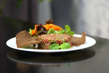 Gurmeler için çiğ et tartarı. Çiğ et tartar, baharat, kızarmış ekmek ve otlar. Kaparili sığır eti. Ekmek dilimli sığır eti..