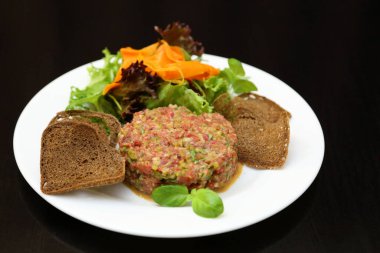 Gurmeler için çiğ et tartarı. Çiğ et tartar, baharat, kızarmış ekmek ve otlar. Kaparili sığır eti. Ekmek dilimli sığır eti..