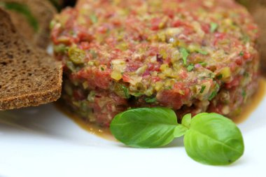 Gurmeler için çiğ et tartarı. Çiğ et tartar, baharat, kızarmış ekmek ve otlar. Kaparili sığır eti. Ekmek dilimli sığır eti..