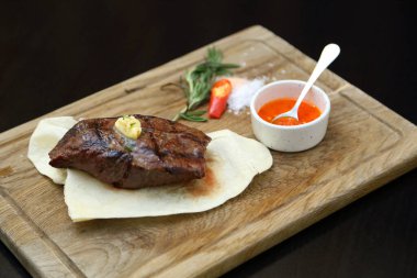 Özel ahşap bir tahtanın üzerindeki pide ekmeğine orta pişmiş biftek. Tahtada biftek var..