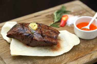 Özel ahşap bir tahtanın üzerindeki pide ekmeğine orta pişmiş biftek. Tahtada biftek var..