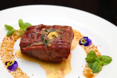 Beyaz tabakta biftek. Biftek mükemmeldi. Orta pişmiş biftek, güzel servis edilmiş beyaz bir tabakta..