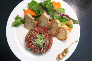 Gurmeler için çiğ et tartarı. Çiğ et tartar, baharat, kızarmış ekmek ve otlar. Kaparili sığır eti. Ekmek dilimli sığır eti..