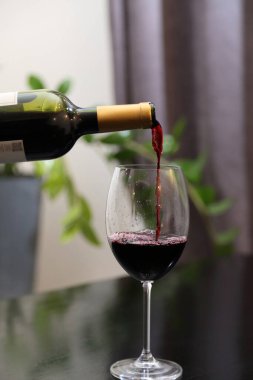 Şarap şişeden bardağa dökülür. Kırmızı şarap bardağa dökülür.