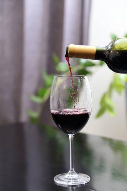 Şarap şişeden bardağa dökülür. Kırmızı şarap bardağa dökülür.
