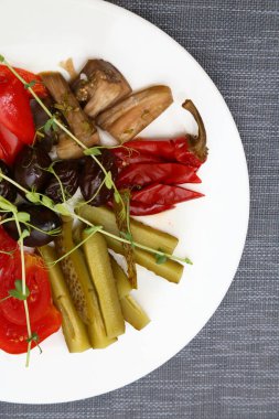 Salamura domates, lahana, salatalık, patlıcan, kırmızı biber, erik. Beyaz tabakta turşu. Restoranda çeşitli sebze turşusu servis ediyorlar.