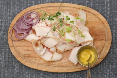 İnce dilimlenmiş domuz yağı, soğan ve hardal. Tahtaya soğan ve hardal konmuş domuz yağı.