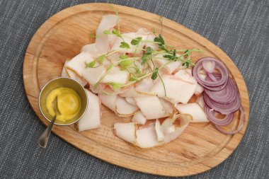 İnce dilimlenmiş domuz yağı, soğan ve hardal. Tahtaya soğan ve hardal konmuş domuz yağı.