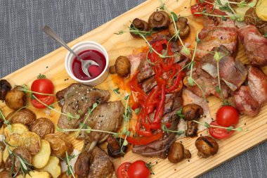 Aperatifleri olan büyük bir tahta tahta: ördek, biftek, mantar, domates ve dört kişi için çeşitli soslar. Mükemmel et ve sebze aperatifleri olan kocaman tahta bir tahta..