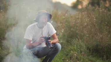 Erkek fotoğrafçı vahşi doğada gün batımında güzel bir manzara yaratıyor. Açık havada çalışan bir fotoğrafçı. Fotoğraf avı. Akşam güneşinde işini yapan fotoğrafçı.. 