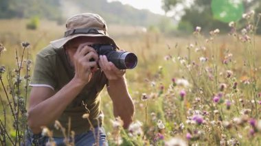 Erkek fotoğrafçı vahşi doğada gün batımında güzel bir manzara yaratıyor. Açık havada çalışan bir fotoğrafçı. Fotoğraf avı. Akşam güneşinde işini yapan fotoğrafçı.. 